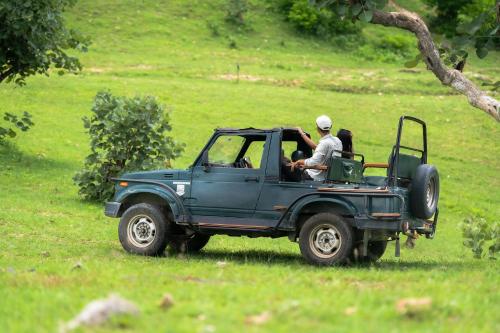 a man driving a green jeep in a field at The Sky Imperial Jungle Camp Resort in Kumbhalgarh