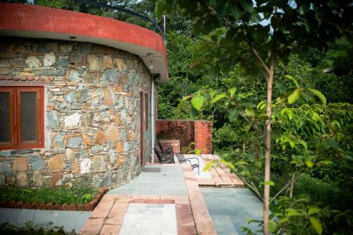 a stone building with a bench in a garden at The Sky Imperial Jungle Camp Resort in Kumbhalgarh