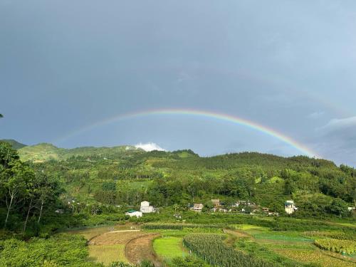 a rainbow in the sky over a farm field at Moc's House bắc hà in Bắc Hà