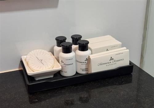 a shelf with four bottles of soap and a box at Methavalai Residence Hotel in Bangkok
