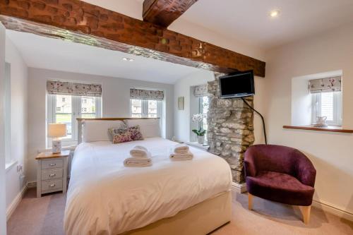 una camera da letto con un letto grande e una sedia di Well Cottage - West Burton a West Burton