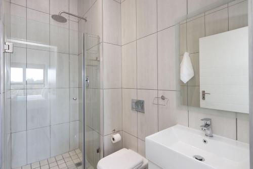 a bathroom with a shower and a toilet and a sink at Atlantic Port 9 by Host Agents in Bloubergstrand