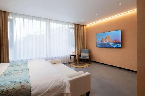 a hotel room with a bed and a tv on the wall at Shugang-Xihuxi Lake Scenic Area Xihu Yushuli B&B in Yangzhou