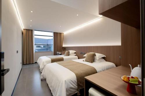 a hotel room with two beds and a table at Shugang-Xihuxi Lake Scenic Area Xihu Yushuli B&B in Yangzhou