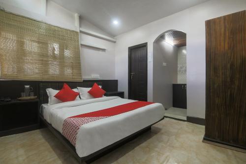 a bedroom with a large bed with red pillows at Hotel O Pillars House in Shillong