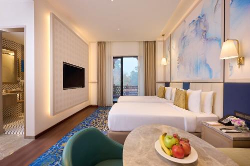a hotel room with two beds and a table with a bowl of fruit at Sarovar Premiere Amritsar in Amritsar