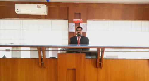 a man sitting at a table in an office at Super Townhouse Dona Castle in Kollam