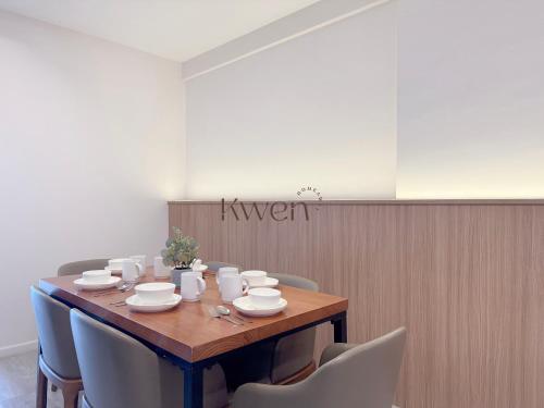 a wooden table with chairs and cups and plates on it at KWEN Suites-Tanjung Aru InfinityPool Seaview/Airport View in Kota Kinabalu