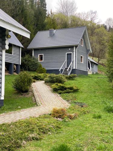 a gray house with a pathway in front of it at Котеджі Віват in Oryavchyk