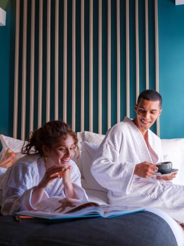 a man and a woman sitting on a bed reading a book at Kaan Casablanca in Casablanca