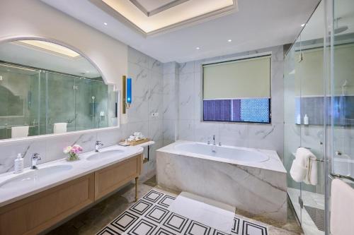 a bathroom with two sinks and a tub and a shower at Sarovar Premiere Amritsar in Amritsar