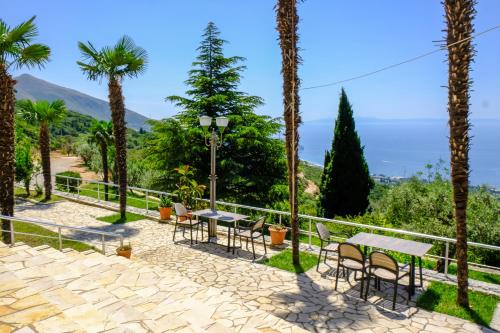 a patio with tables and chairs and palm trees at Hotel Palasa in Palasë