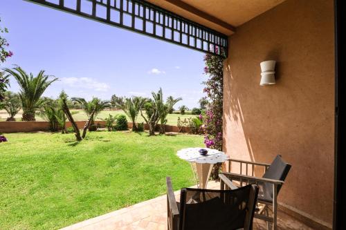 a patio with a table and chairs and a green yard at Pickalbatros Hôtel Du Golf - Adults Friendly 16 Years Plus- All-Inclusive in Marrakech