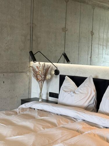 a bed with a lamp and a vase of flowers on a table at Apartament Odlot in Międzybrodzie Żywieckie