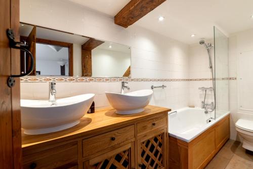 a bathroom with two sinks and a tub and a toilet at Cae Madog Barn in Llanbrynmair