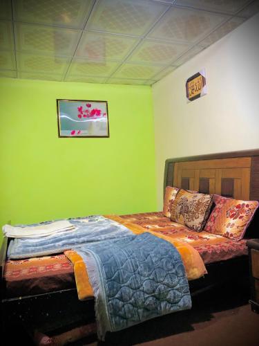 a bedroom with a bed with a green wall at 4 Season Guest House Naltar in Gilgit