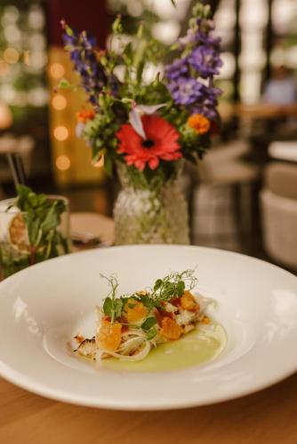 a plate of food on a table with a vase of flowers at WestCord Hotel Eindhoven in Eindhoven