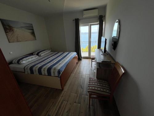 a bedroom with a bed and a desk and a window at Apartman Leo in Brela