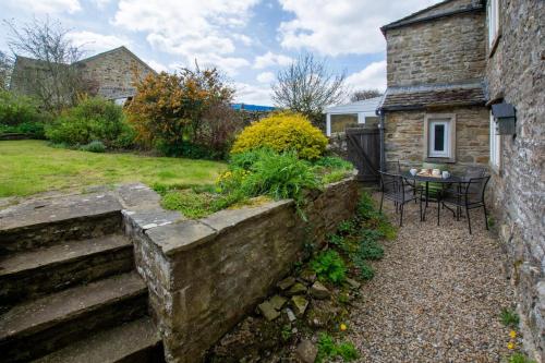 a garden with a stone wall next to a house at Lyncroft in Aysgarth