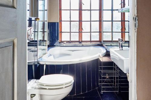 a bathroom with a toilet and a tub and a sink at Boord Guest House in Stellenbosch