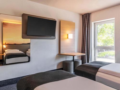 a hotel room with two beds and a flat screen tv at B&B HOTEL Eschweiler in Eschweiler
