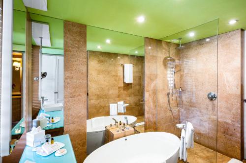 a bathroom with a tub and a sink and a shower at Pickalbatros Hôtel Du Golf - Adults Friendly 16 Years Plus- All-Inclusive in Marrakech