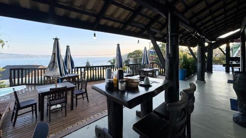 a restaurant with tables and chairs on a wooden deck at Pousada Caminho do Mar in Bombinhas