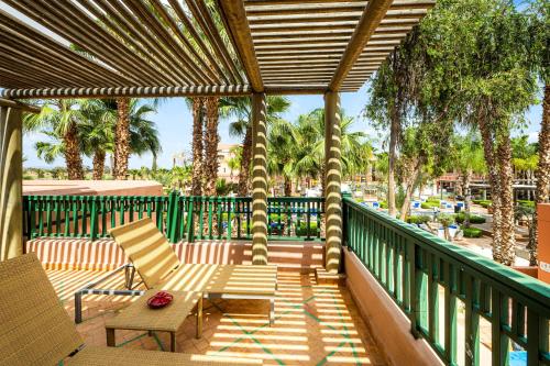 a patio with two chairs and a table on a deck at Pickalbatros Hôtel Du Golf - Adults Friendly 16 Years Plus- All-Inclusive in Marrakech