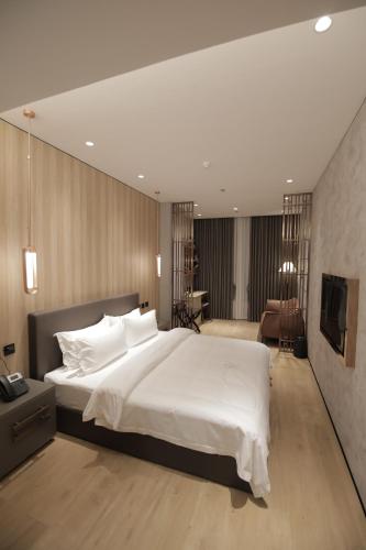 a bedroom with a large white bed and a desk at LOTUS BLU HOTEL Naga 