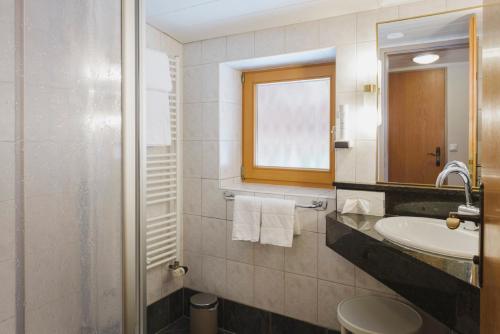 a bathroom with a sink and a toilet and a mirror at Hotel Acherl in Achenkirch