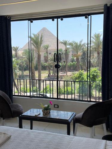 a room with a bed and a large window with palm trees at Miracle Pyramids View Hotel in Giza
