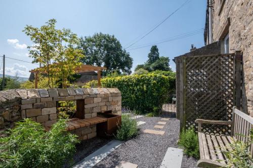 a garden with a stone wall and a bench at Wayside in Carperby