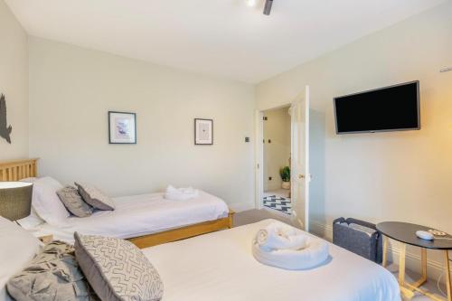 a room with two beds and a tv on the wall at Wayside in Carperby