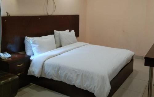 a bed with white sheets and pillows in a room at Elet Business Hotel in Karachi
