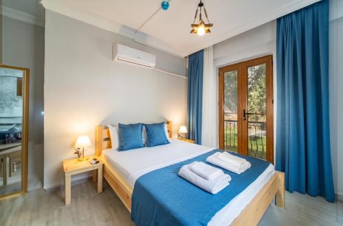 a bedroom with a bed with blue sheets and blue curtains at Saygın Otel Selimiye in Selimiye