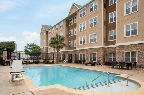 a pool with tables and chairs in front of a building at Residence Inn by Marriott Houston Katy Mills in Katy