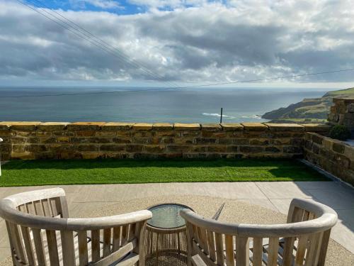 two chairs sitting on a patio overlooking the ocean at 1 Browcote Cottage in Ravenscar