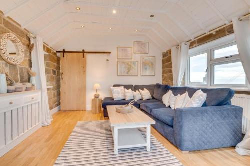 a living room with a blue couch and a table at 1 Browcote Cottage in Ravenscar