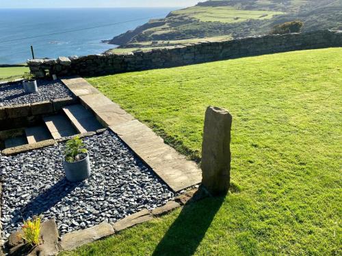 a stone path on a hill with the ocean in the background at 1 Browcote Cottage in Ravenscar