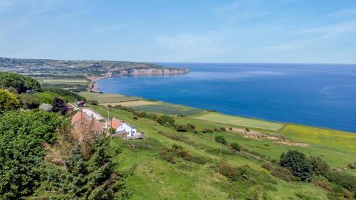 an aerial view of a house on a hill next to the ocean at 1 Browcote Cottage in Ravenscar