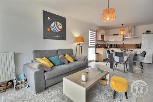 un salon avec un canapé et une table et une cuisine dans l'établissement Le saint quay plage, à Saint-Quay-Portrieux