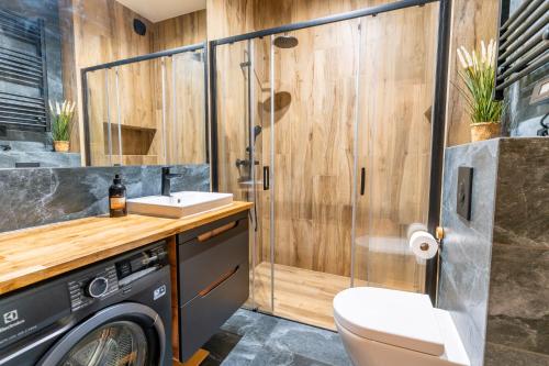 a bathroom with a shower and a washing machine at Omega Lake Apartments in Olsztyn