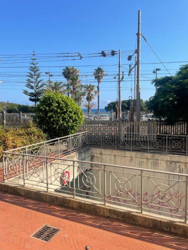 a concrete retaining wall with a fence and palm trees at casa ibisco-50m dal mare in Bordighera