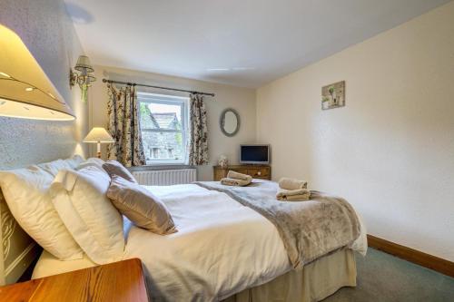 ein Schlafzimmer mit großem Bett und Fenster in der Unterkunft West Cottage in Thwaite