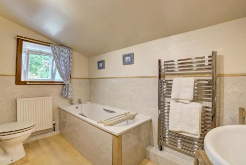 ein Badezimmer mit Badewanne, Toilette und Waschbecken in der Unterkunft West Cottage in Thwaite