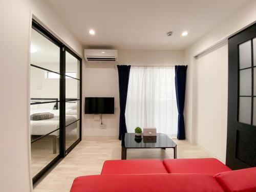 a living room with a red couch and a bed at GLITTER302 Max 6ppl 5 minutes to USJ by train in Osaka