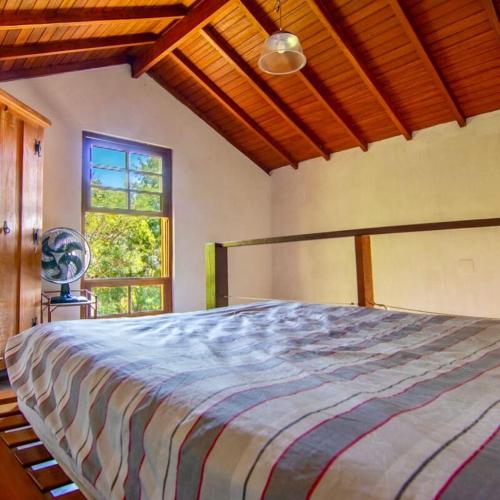 un grand lit dans une chambre avec une fenêtre dans l'établissement Vila Costa Sul Chalés e Estúdios, à Ilhabela