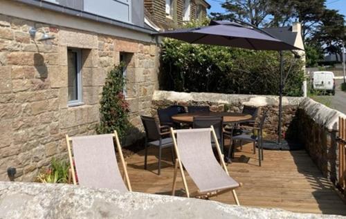a patio with a table and chairs and an umbrella at La Chaumière en bord de mer in Trégastel