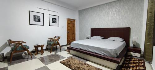 a bedroom with a bed and two chairs and a table at The Hill Crest, Fagu in Shimla