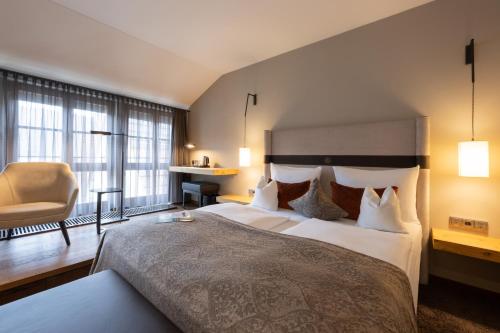 a hotel room with a large bed and a chair at Hotel Goldene Sonne in Landshut
